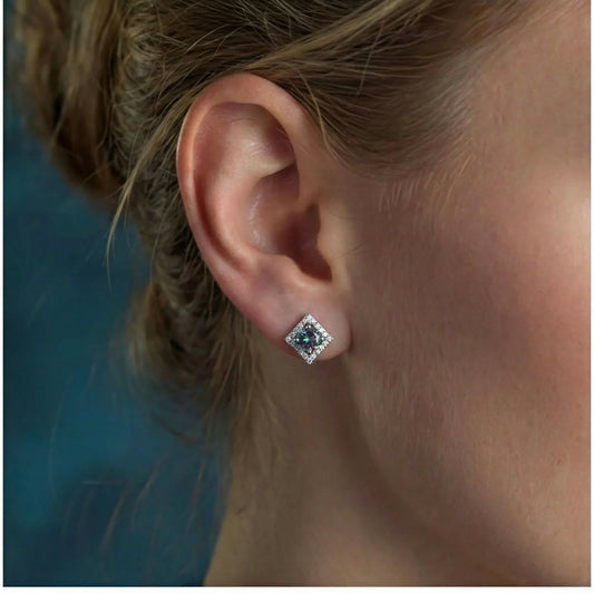 Square stud earring with central gemstone and diamond halo, worn on earlobe
