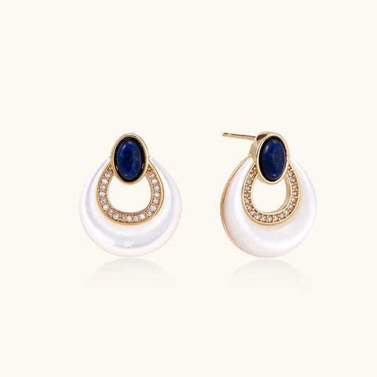 Elegant gold earrings with blue stone and crystal accents on white pearl-like base