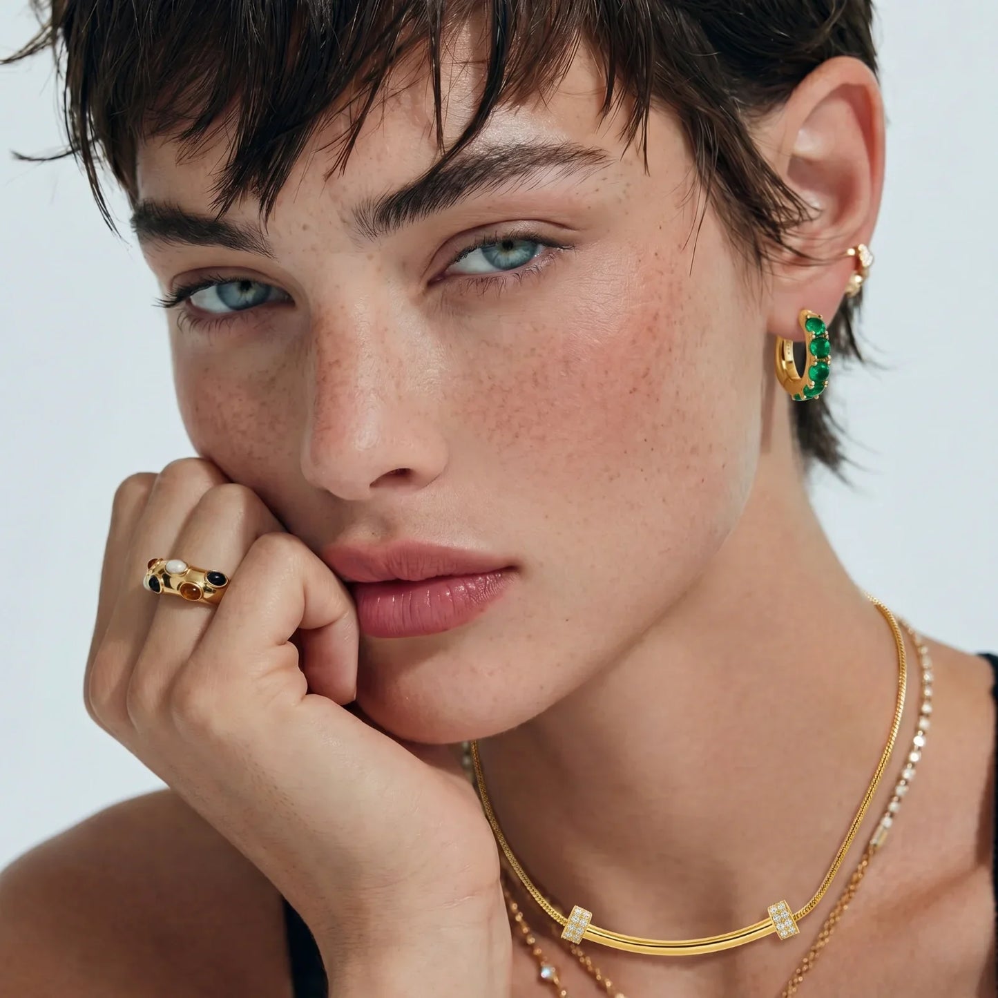 Elegant gold jewelry set with emerald hoop earrings, multi-stone ring, and diamond-accent necklaces