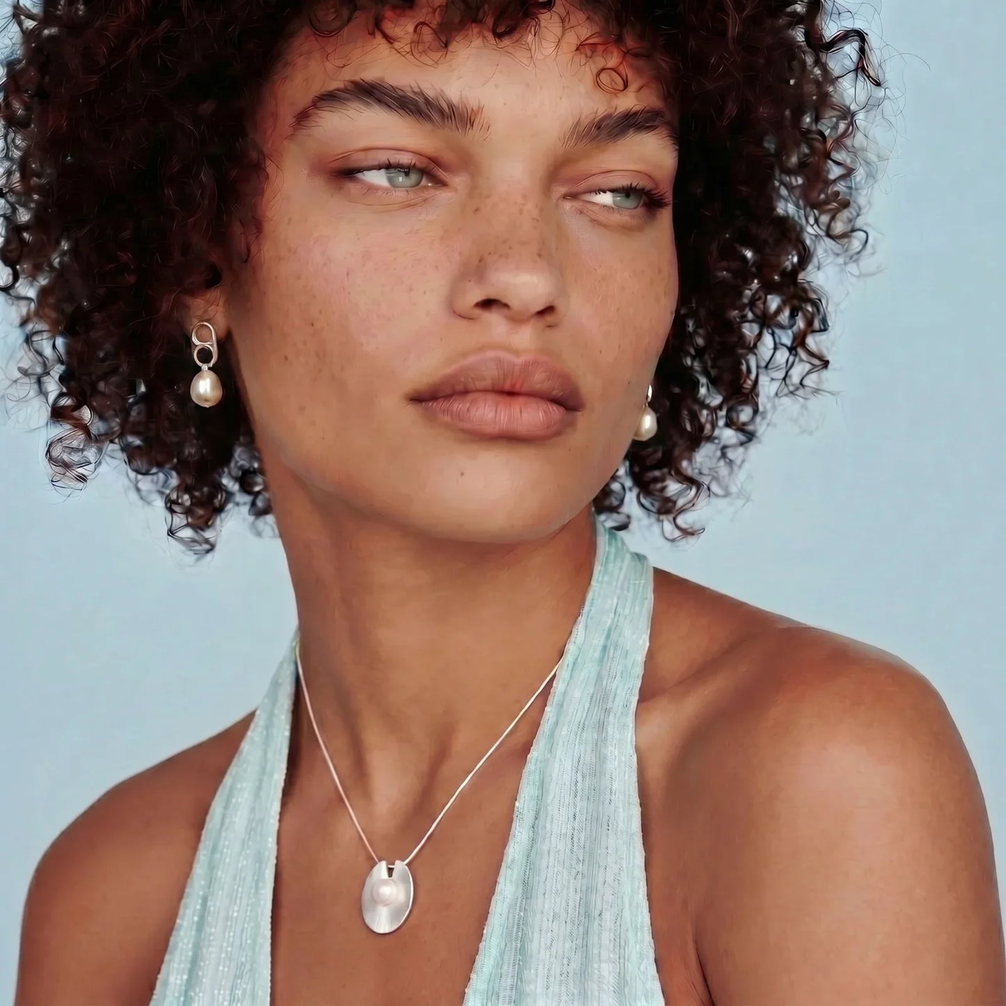 Woman wearing pearl drop earrings and silver pendant necklace, styled for elegant home décor gifting