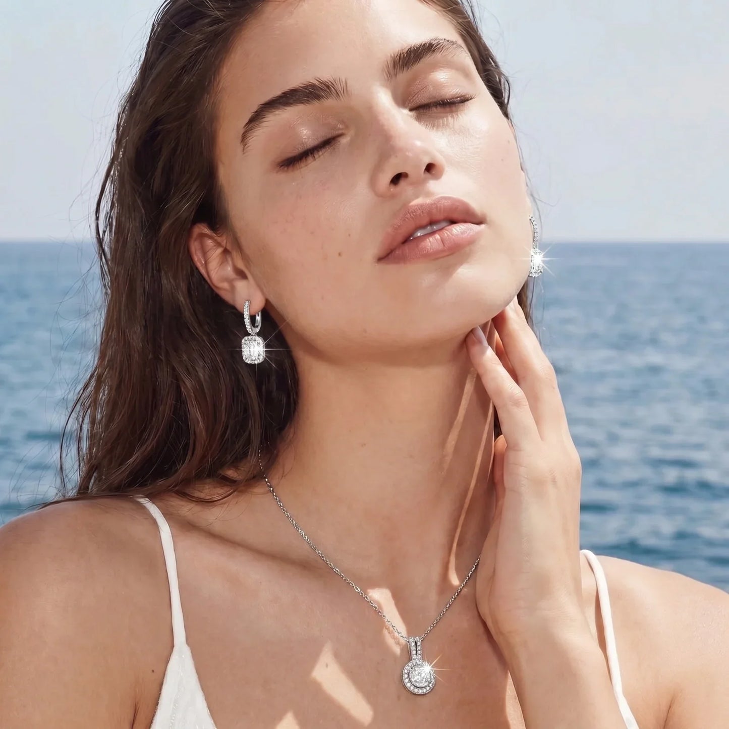 Elegant diamond hoop earrings and pendant necklace worn by woman at ocean, sparkling luxury jewelry