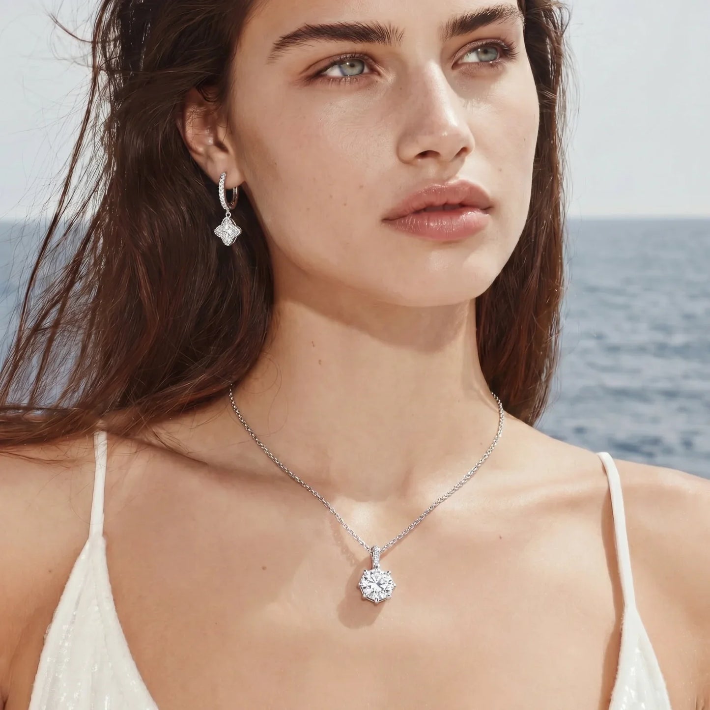 Elegant diamond pendant necklace and matching earrings worn by woman near ocean, perfect for luxury home gifting