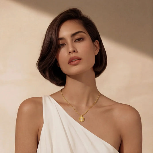 Woman wearing gold sunburst pendant necklace with rope chain, elegant white one-shoulder top