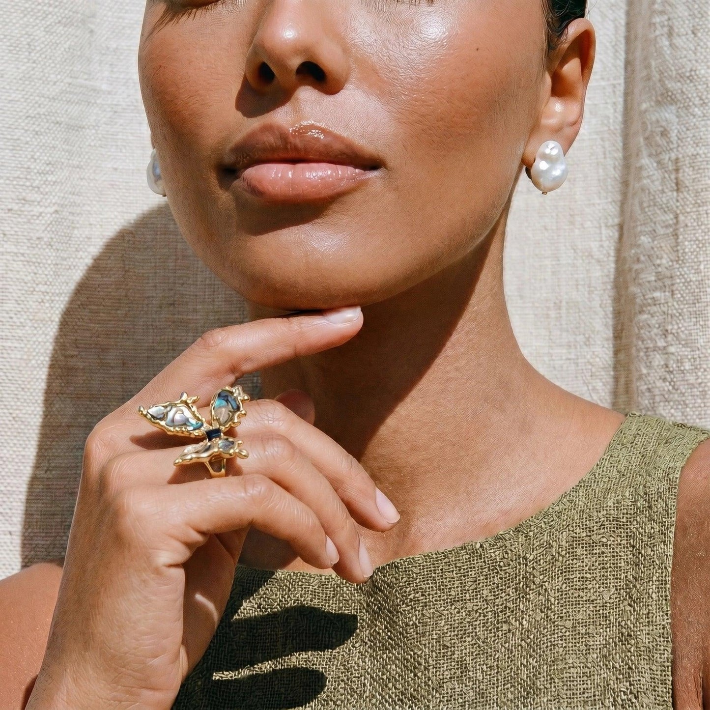 Woman wearing gold butterfly ring with pearl earrings, styled for elegant home décor gifting