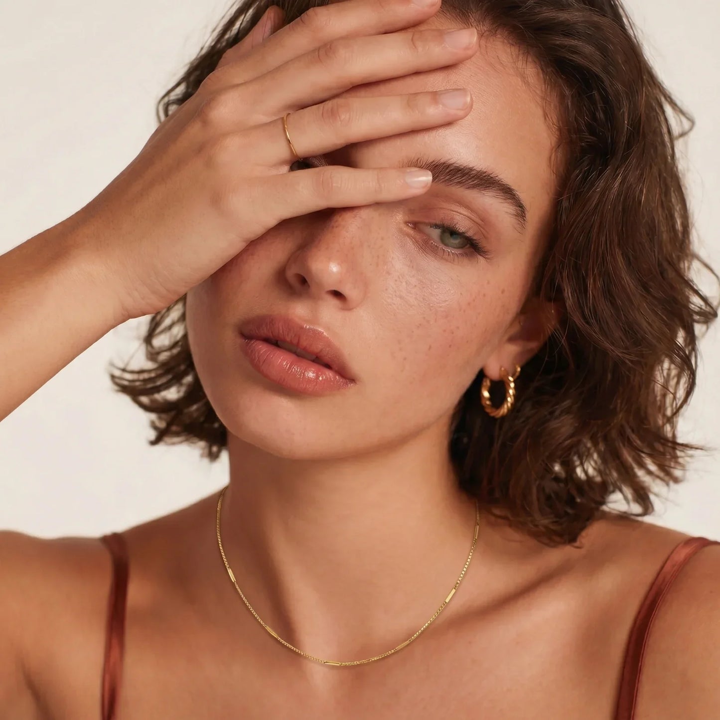 Woman wearing gold hoop earrings, delicate chain necklace, and minimalist ring for elegant everyday style