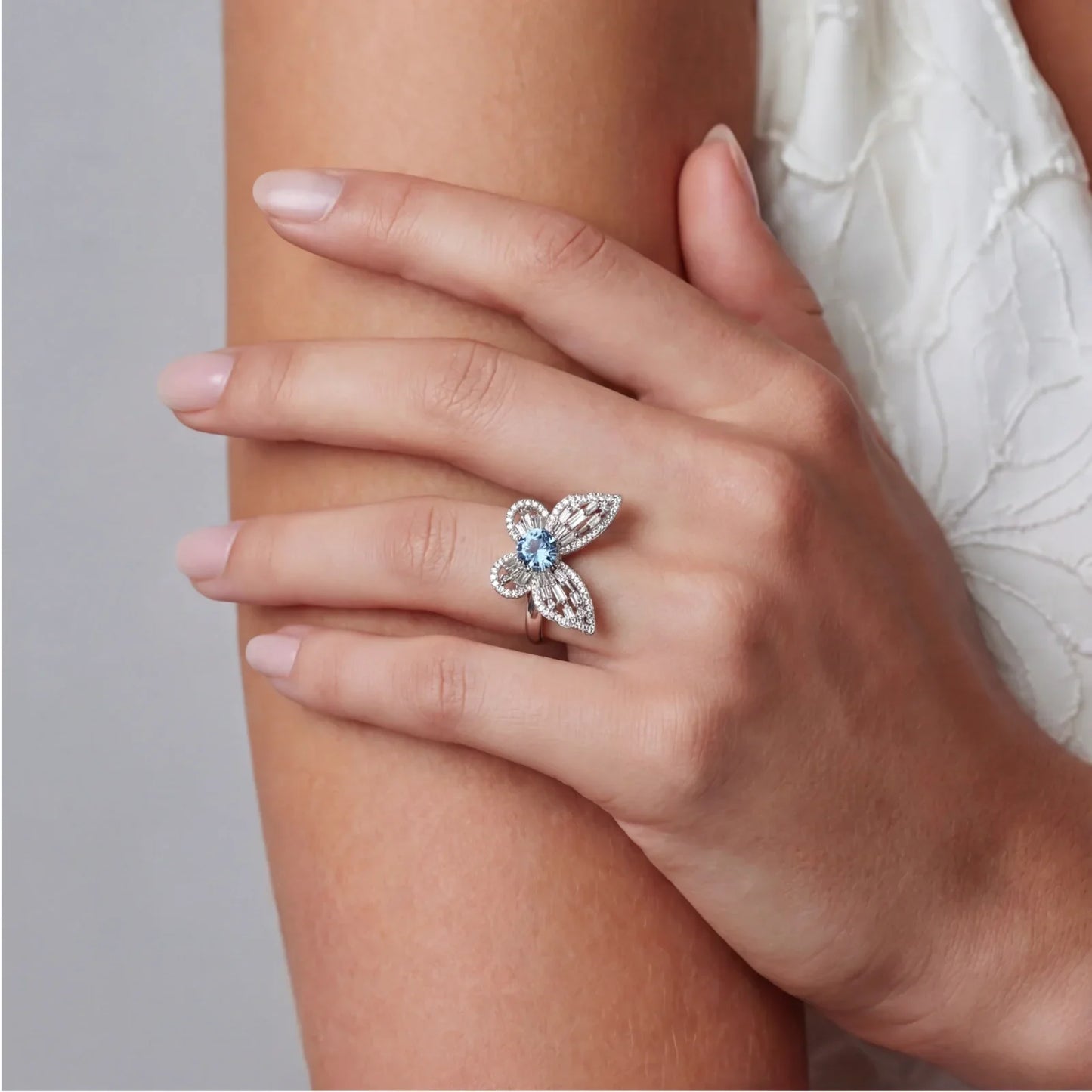 Elegant flower-shaped ring with blue gemstone and diamond accents on woman's hand