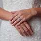 Elegant engagement ring with oval gemstone on bride's hand, white lace wedding dress background