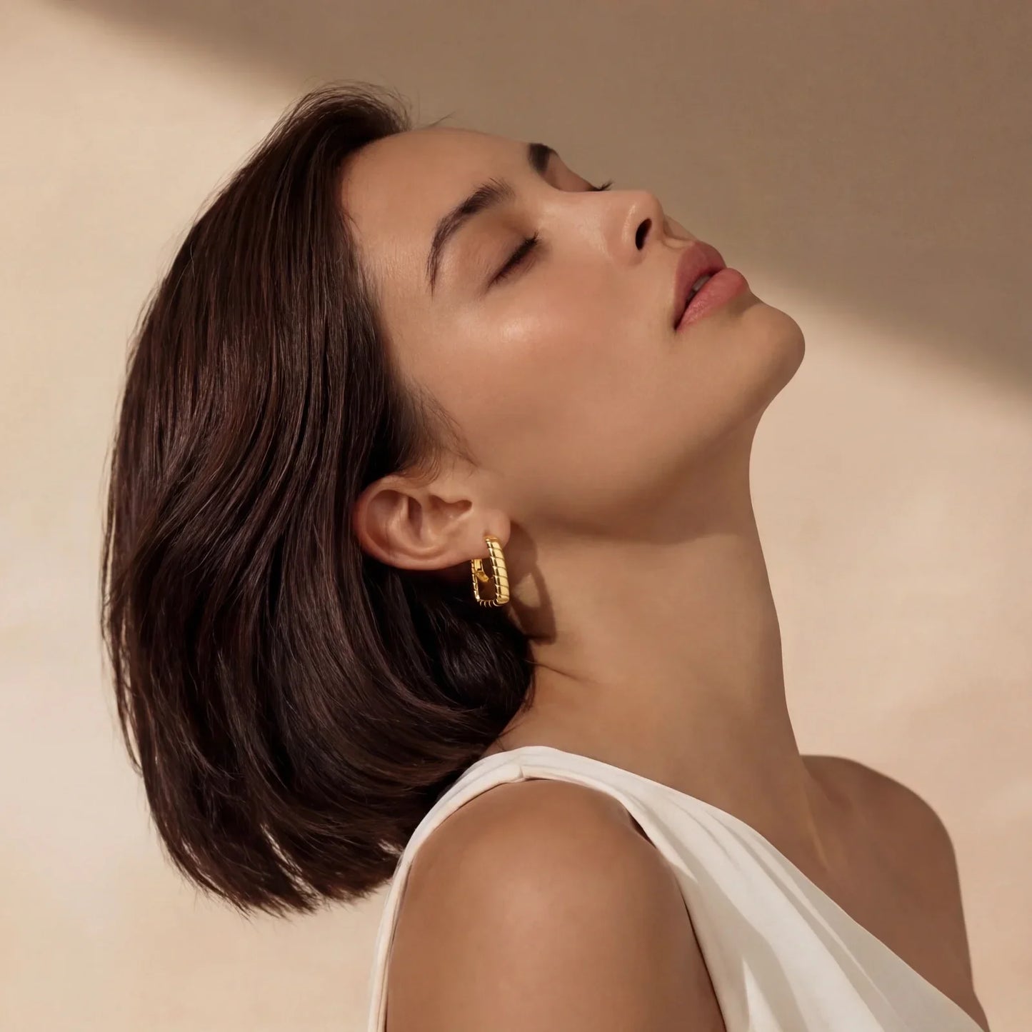 Woman wearing gold hoop earrings, styled with short dark hair and white top, elegant home décor accessory