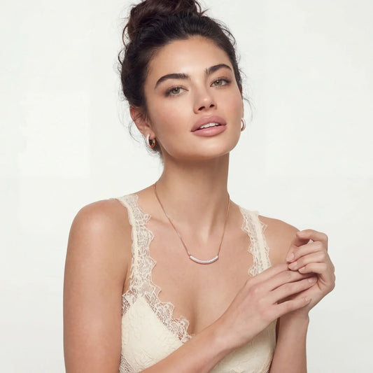 Elegant woman wearing delicate rose gold necklace and hoop earrings with lace top