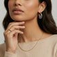 Woman wearing gold chain necklace, colorful hoop earrings, and matching ring, styled for elegant home décor