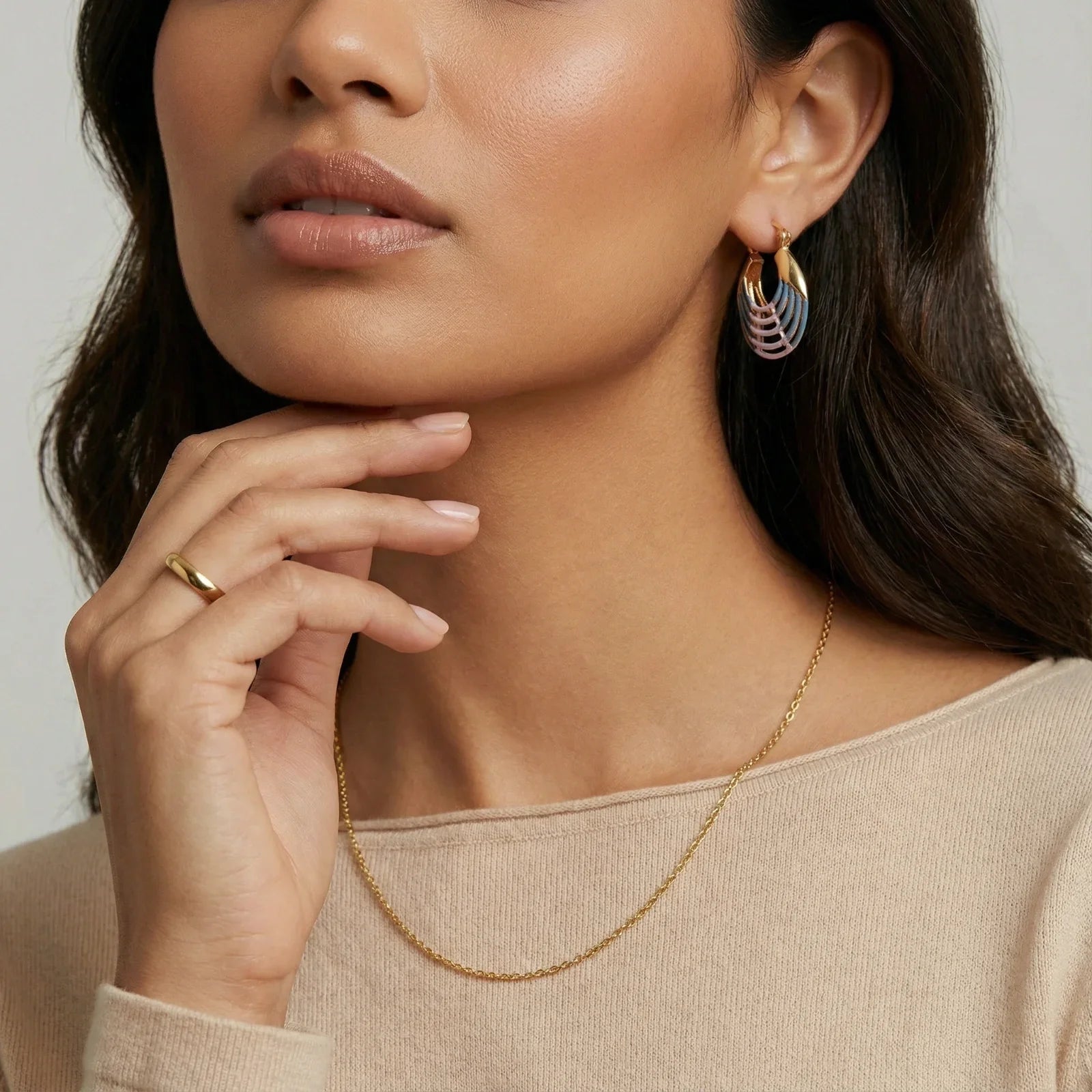 Woman wearing gold chain necklace, colorful hoop earrings, and matching ring, styled for elegant home décor