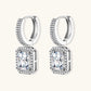 Sterling silver huggie hoops with emerald-cut moissanite drops featuring pavé-set crystals on white background.