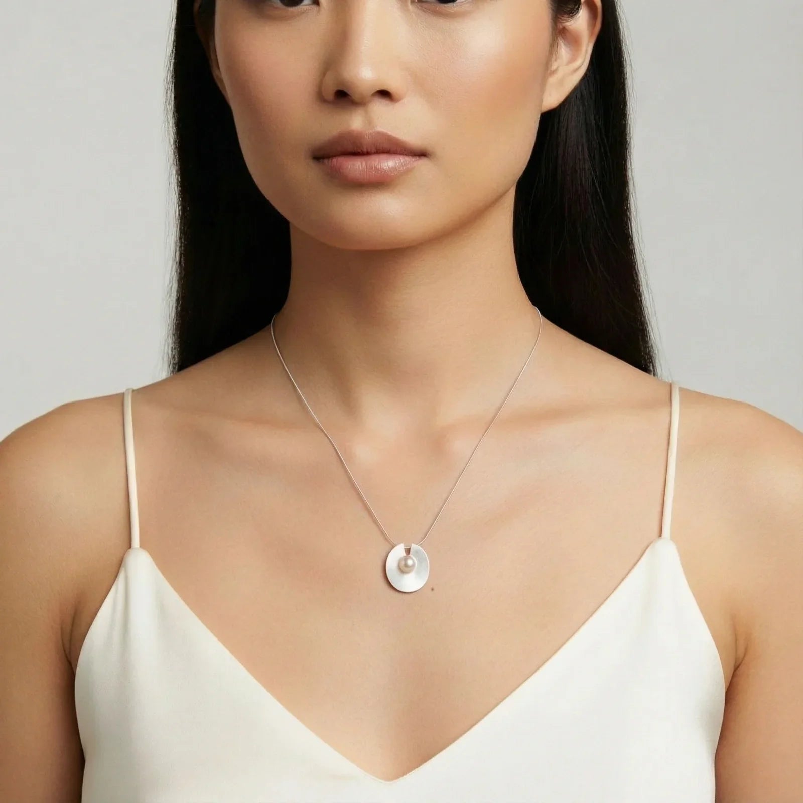 Elegant pearl pendant necklace on woman, minimalist silver disc design, perfect for stylish home décor gifts