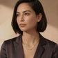 Woman wearing elegant gold bar necklace with diamonds, styled with dark blazer for modern sophistication.