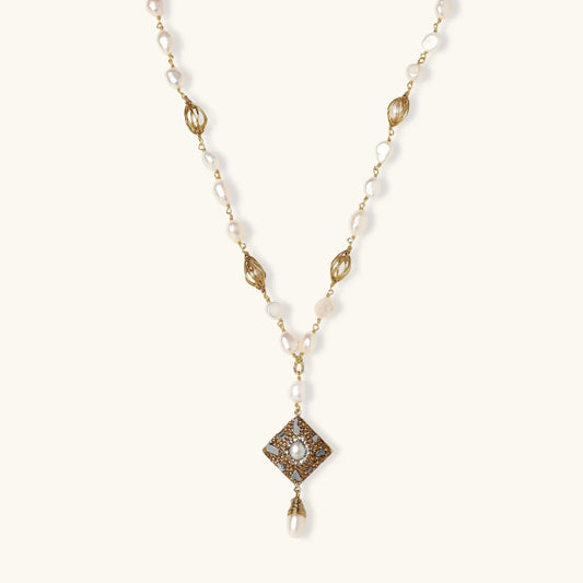 Elegant pearl necklace with gold filigree and diamond-shaped pendant, perfect for luxury home décor gifting.