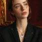 Elegant gold necklace with blue gem and white pendant, worn by woman in black lace top