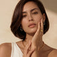 Woman wearing gold chain necklace, hoop earrings, and rings, styled for elegant home décor