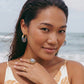 Woman wearing gold hoop earrings and cameo ring at beach, stylish summer jewelry