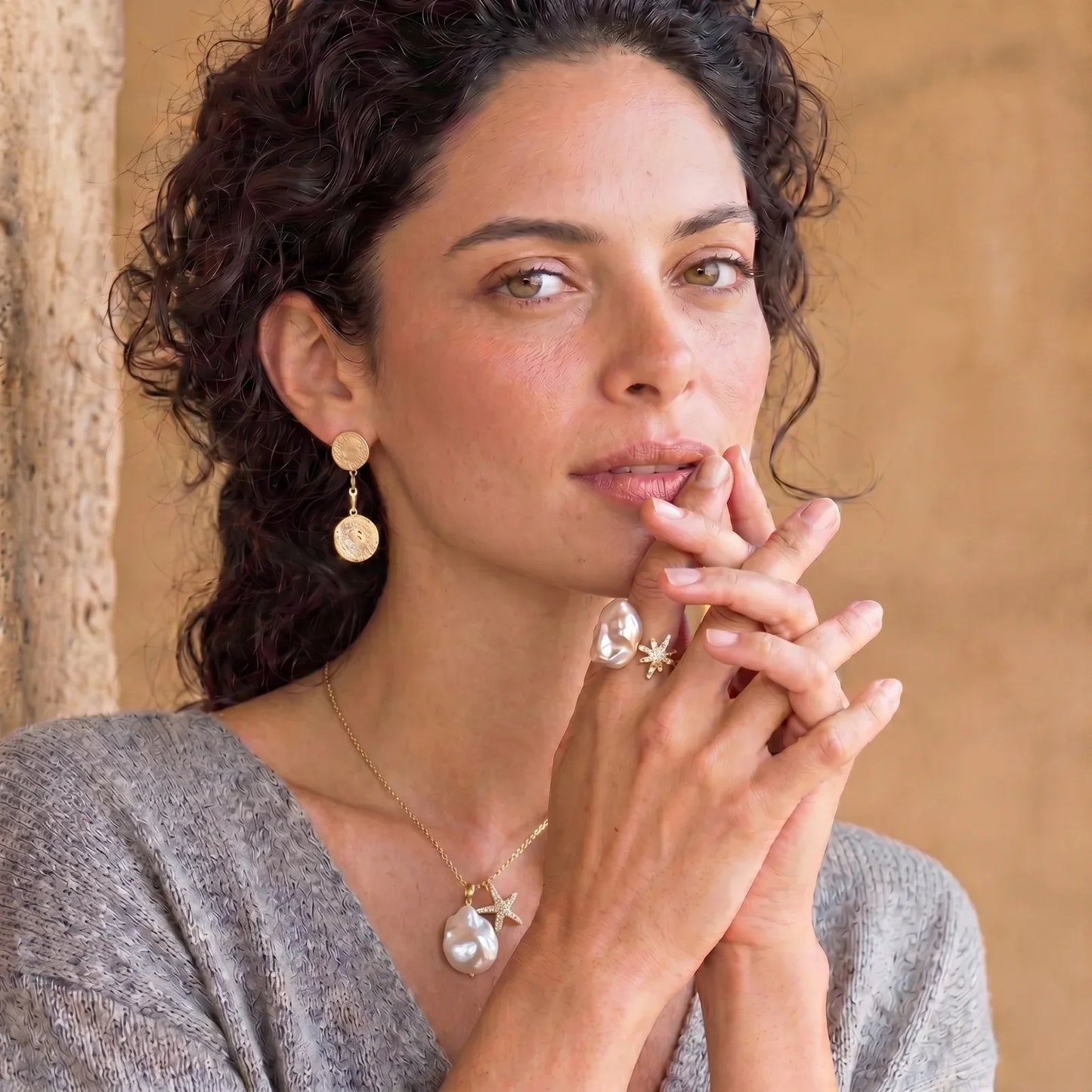 Woman wearing gold coin earrings, baroque pearl necklace, and starfish rings, styled for elegant home décor gifting.