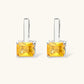 Silver curb-chain necklace and hoop drop earrings set with paired yellow and clear square zirconia stones.