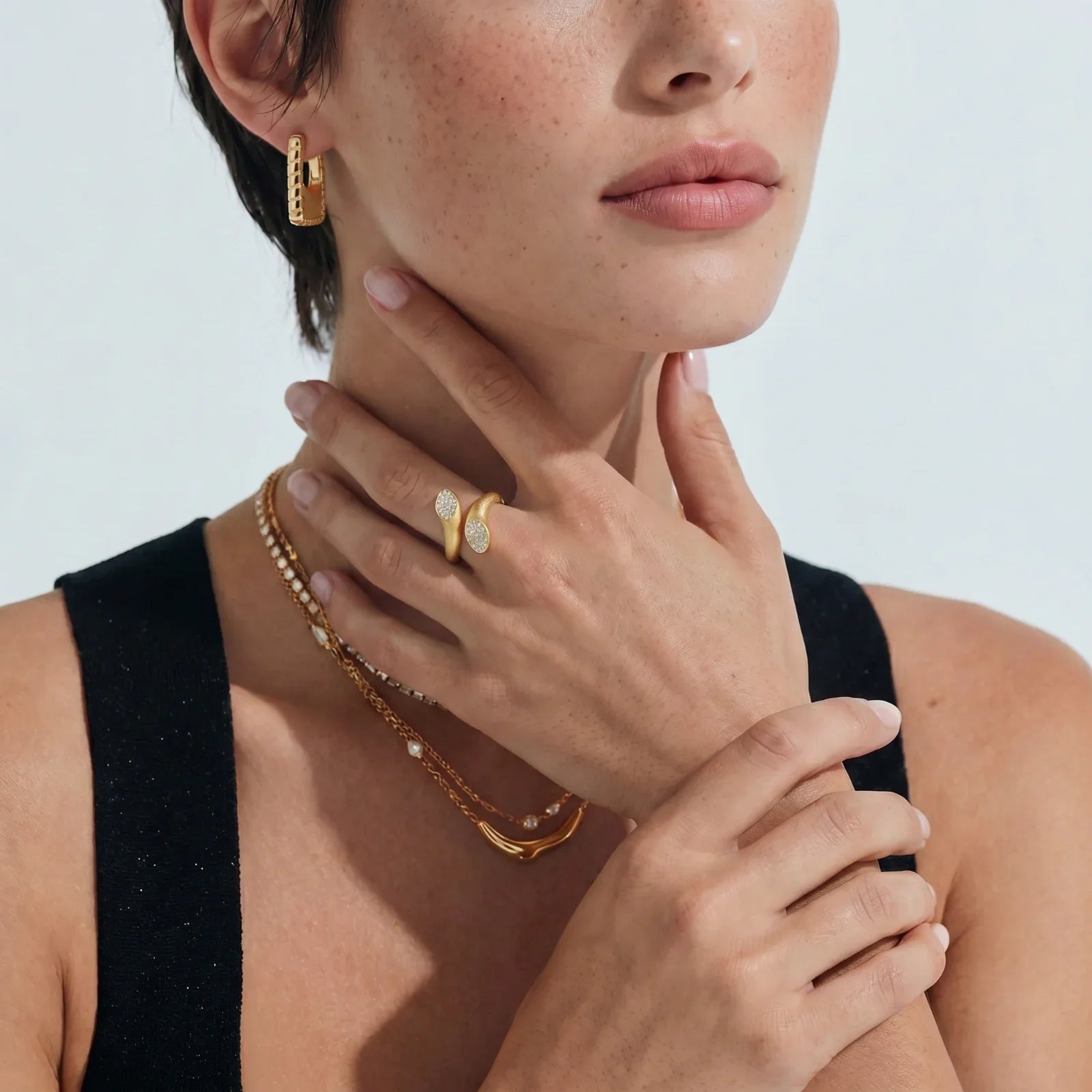 Gold hoop earrings, layered pearl necklaces, and diamond-accent rings on model