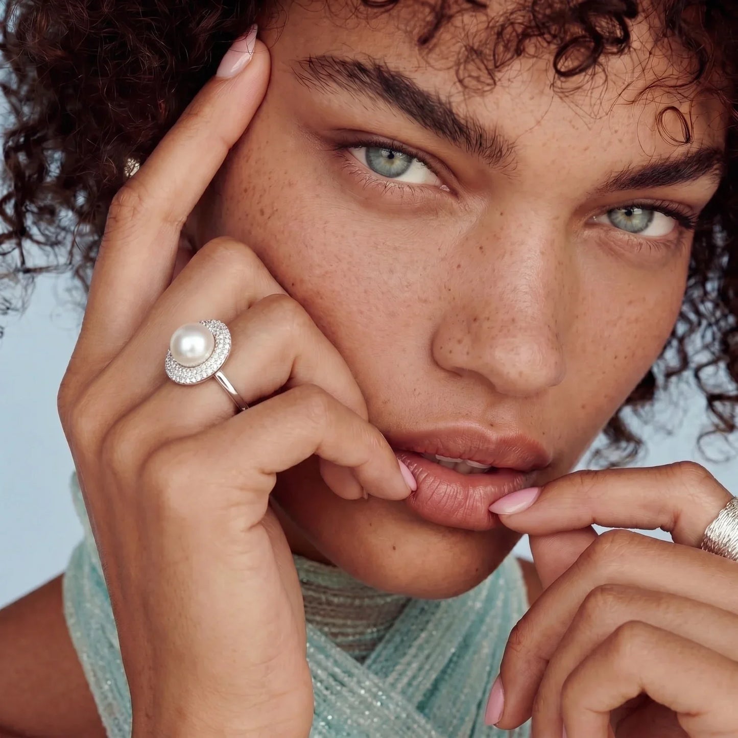 Elegant pearl ring with crystal halo, styled on model with curly hair and soft makeup