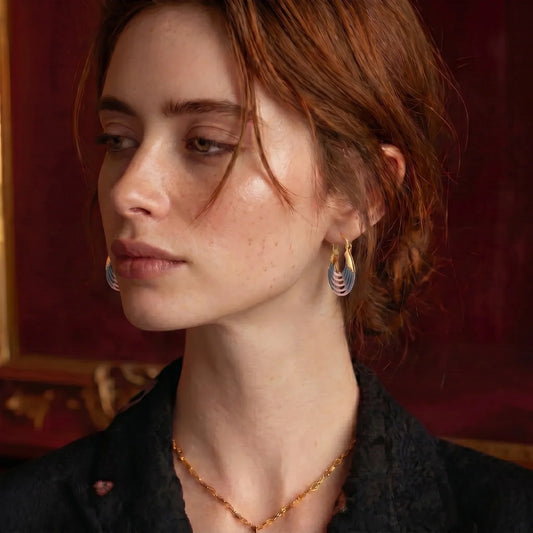 Woman wearing gold chain necklace and blue-gold layered hoop earrings, elegant home décor accessory