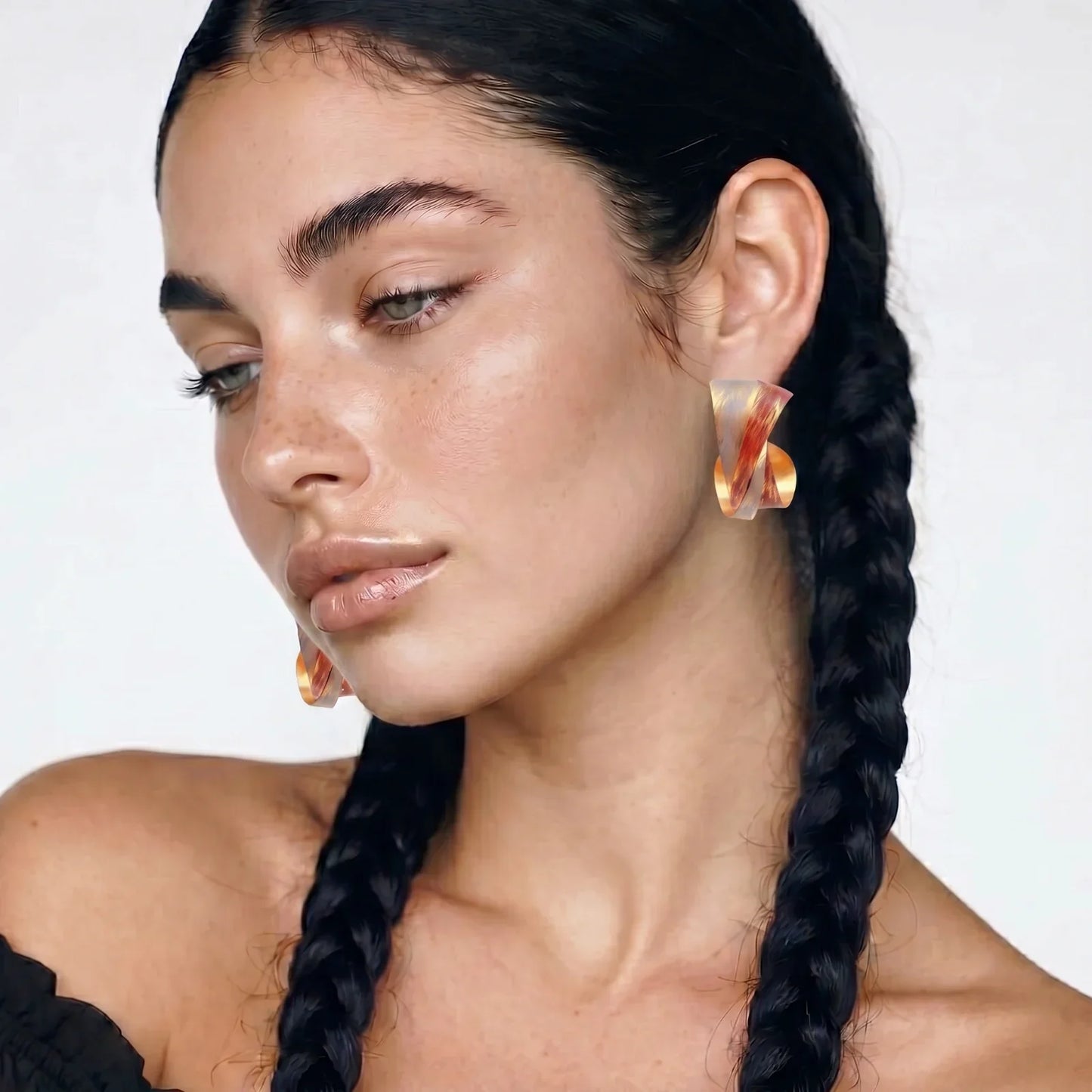 Woman wearing amber resin statement earrings, braided hair, minimalist style