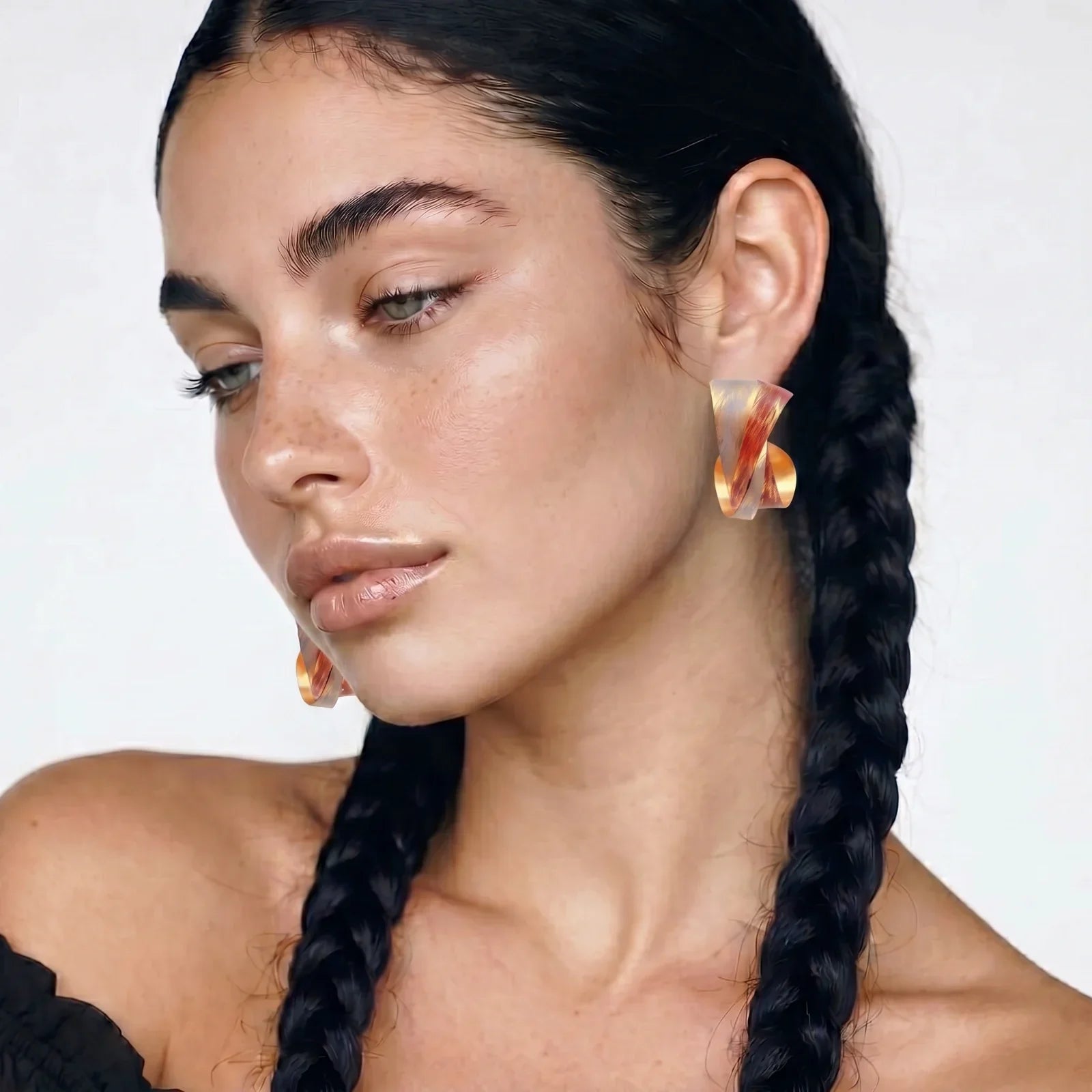 Woman wearing amber resin statement earrings, braided hair, minimalist style