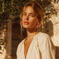 Woman wearing floral drop earrings and white blouse, styled for boho home décor inspiration