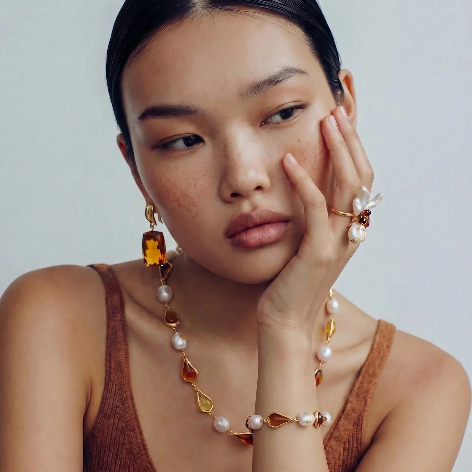 Elegant amber and pearl jewelry set with gold accents, featuring necklace, earrings, bracelet, and ring.
