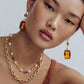Gold chain necklace with amber and pearl drops, paired with matching statement earrings for elegant style