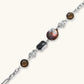Chain bracelet with amber stones, baroque pearl, and dark rectangular stone on white gold-plated copper base.