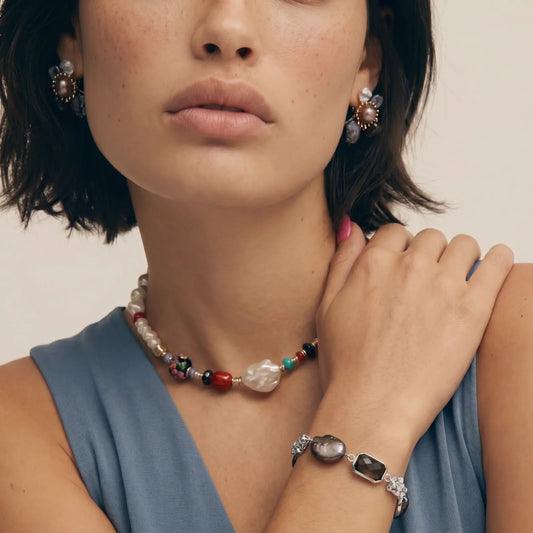 Woman wearing colorful beaded necklace, pearl earrings, and gemstone bracelet for elegant home décor styling