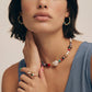 Colorful beaded necklace, gold hoop earrings, and gemstone ring styled for boho home décor lovers