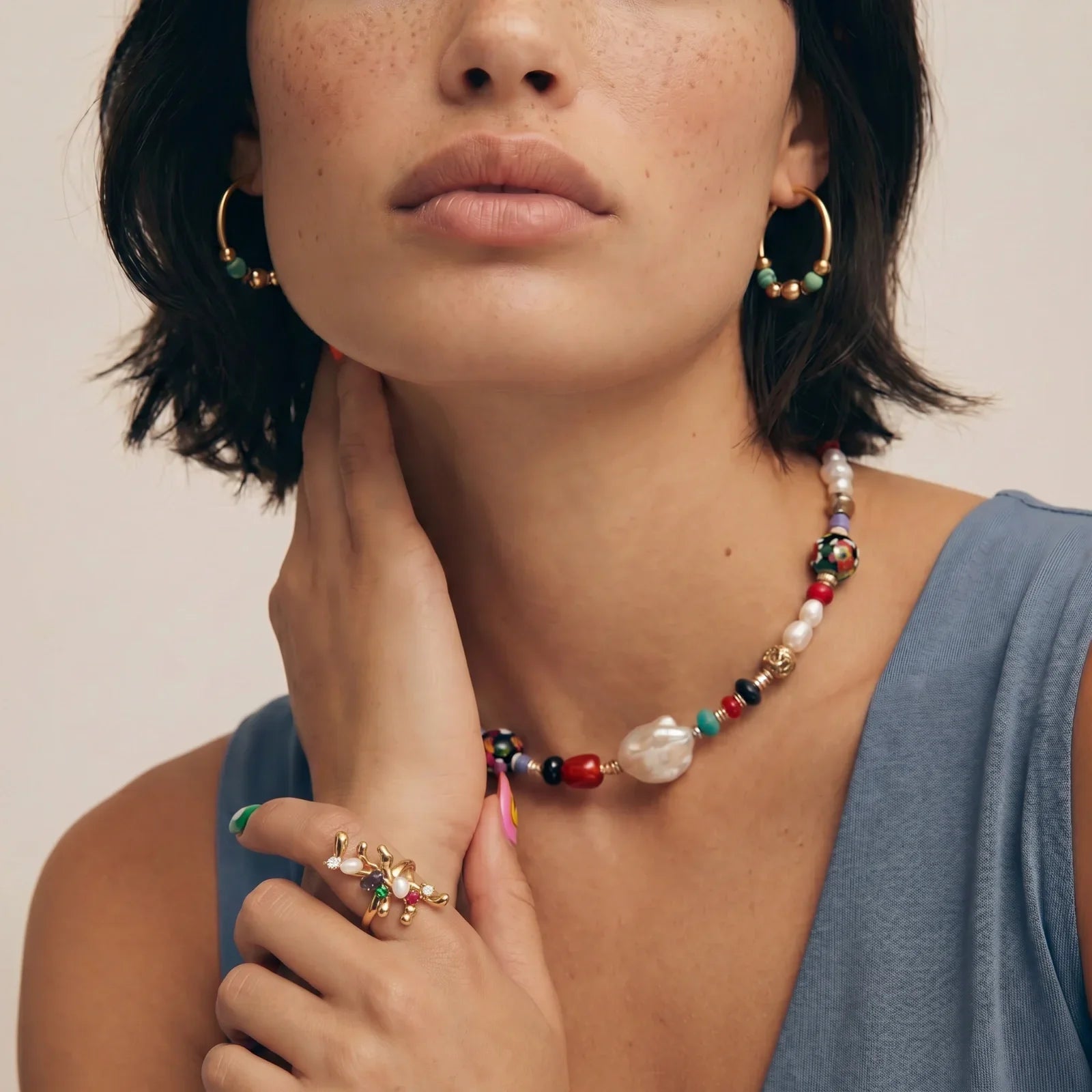 Colorful beaded necklace, gold hoop earrings, and gemstone ring styled for boho home décor lovers