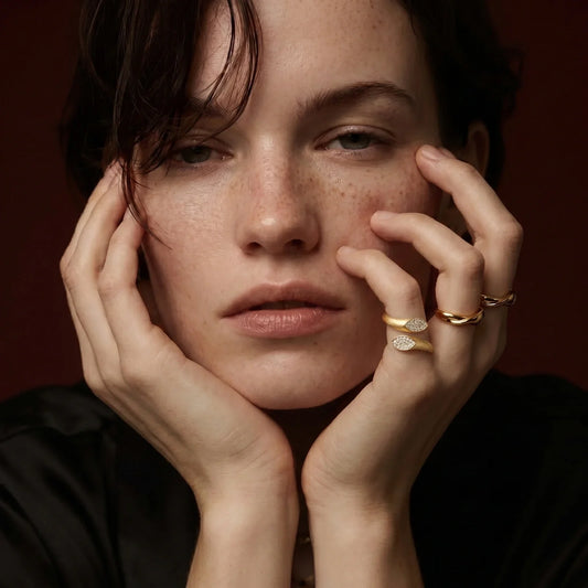 Woman wearing elegant gold rings with diamond accents, showcasing minimalist luxury jewelry.