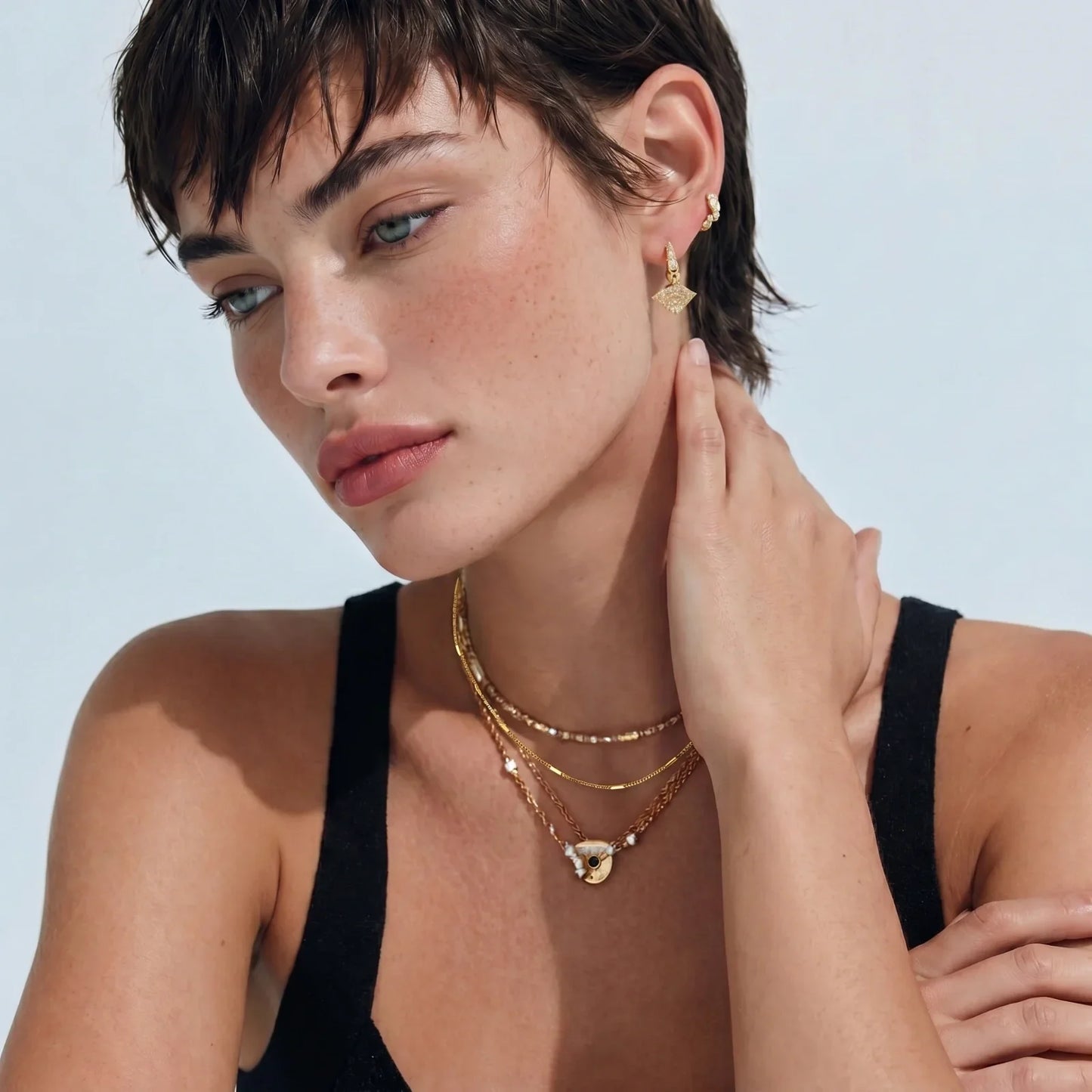 Woman wearing layered gold necklaces and diamond-shaped earrings, stylish home décor accessory
