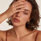 Woman wearing gold hoop earrings, delicate chain necklace, and minimalist ring for elegant everyday style