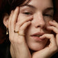 Woman wearing elegant gold rings and hoop earrings, showcasing fine jewelry for everyday style