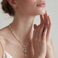 Elegant pearl necklace with turquoise pendant, gold chain, and delicate drop detail worn by woman