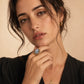 Elegant woman wearing vintage-style cameo ring with pearl accents, gold hoop earrings, and delicate necklace.