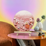 Artisan beach-inspired round wall art with seashells on a pink textured background, displayed on a table in a modern living room. Fansee Australia home decor.