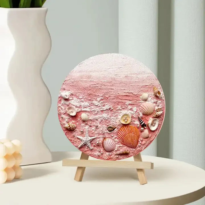 Round artisan home decor plaque with pink beach texture and seashells on small wooden easel