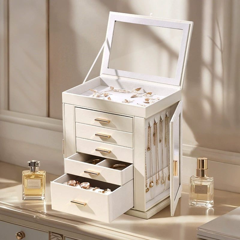 Elegant white jewelry box with gold handles, holding necklaces, rings, and earrings on a vanity.