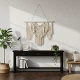 Modern living room with artisan macrame wall hanging, black console table, and indoor plants