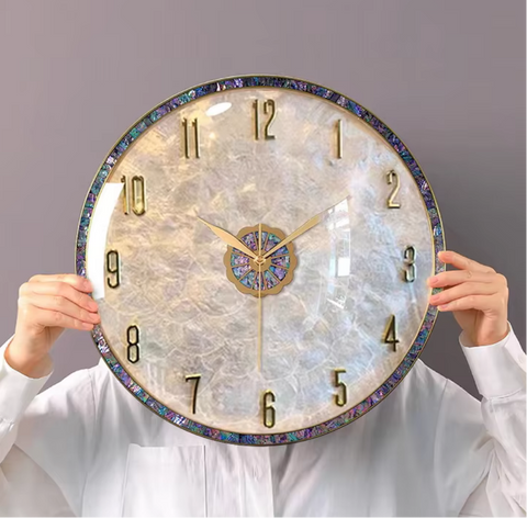 Luxury gold art decor metal round wall clock with iridescent accents, held in front of person, Fansee Australia.