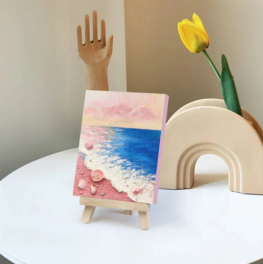 Artisan beach scene painting with textured seashells on mini easel, modern home decor table.