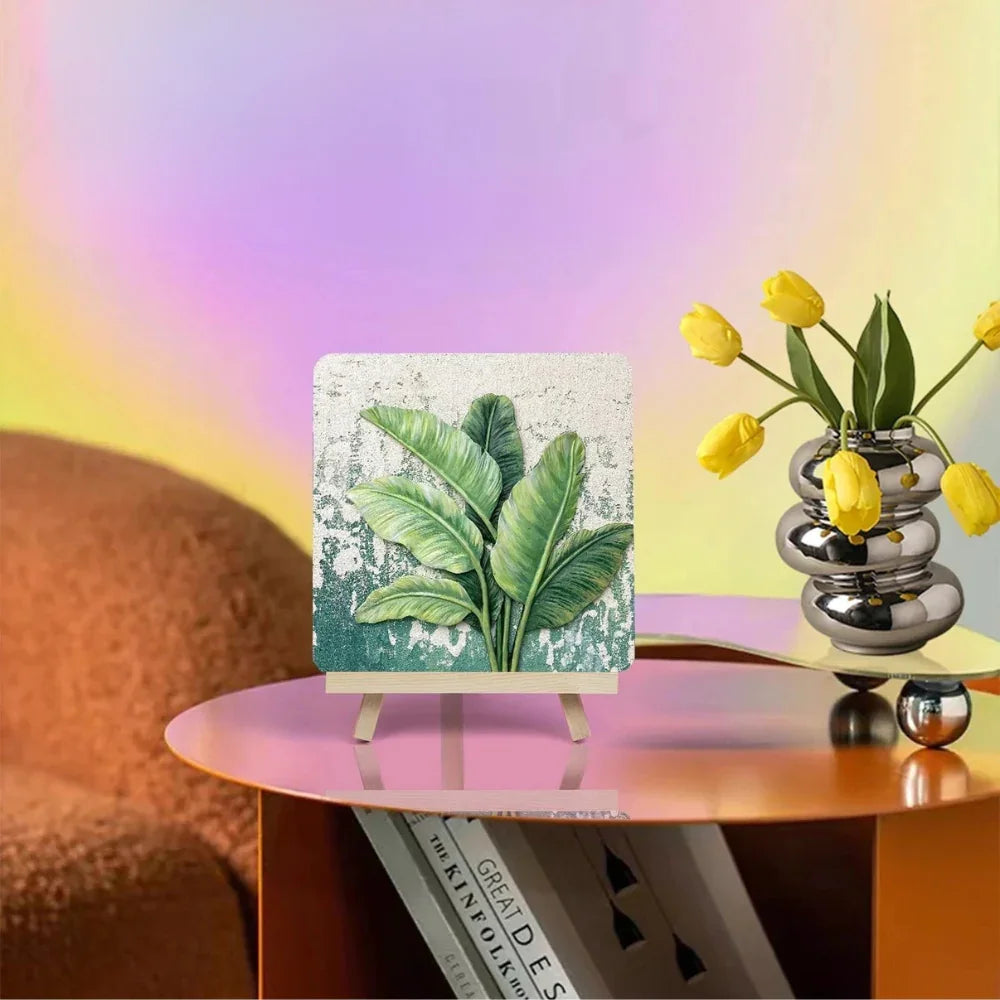 Modern home decor scene with botanical art, silver vase of yellow tulips on pink table