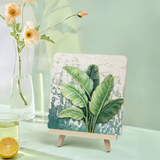 Handcrafted home decor art with green leaves on tabletop, vase with flowers, and lemon drink